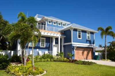 Blue coastal-style house exterior with front porch and landscaped yard
