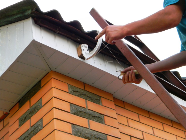 A building contractor is installing rain gutter