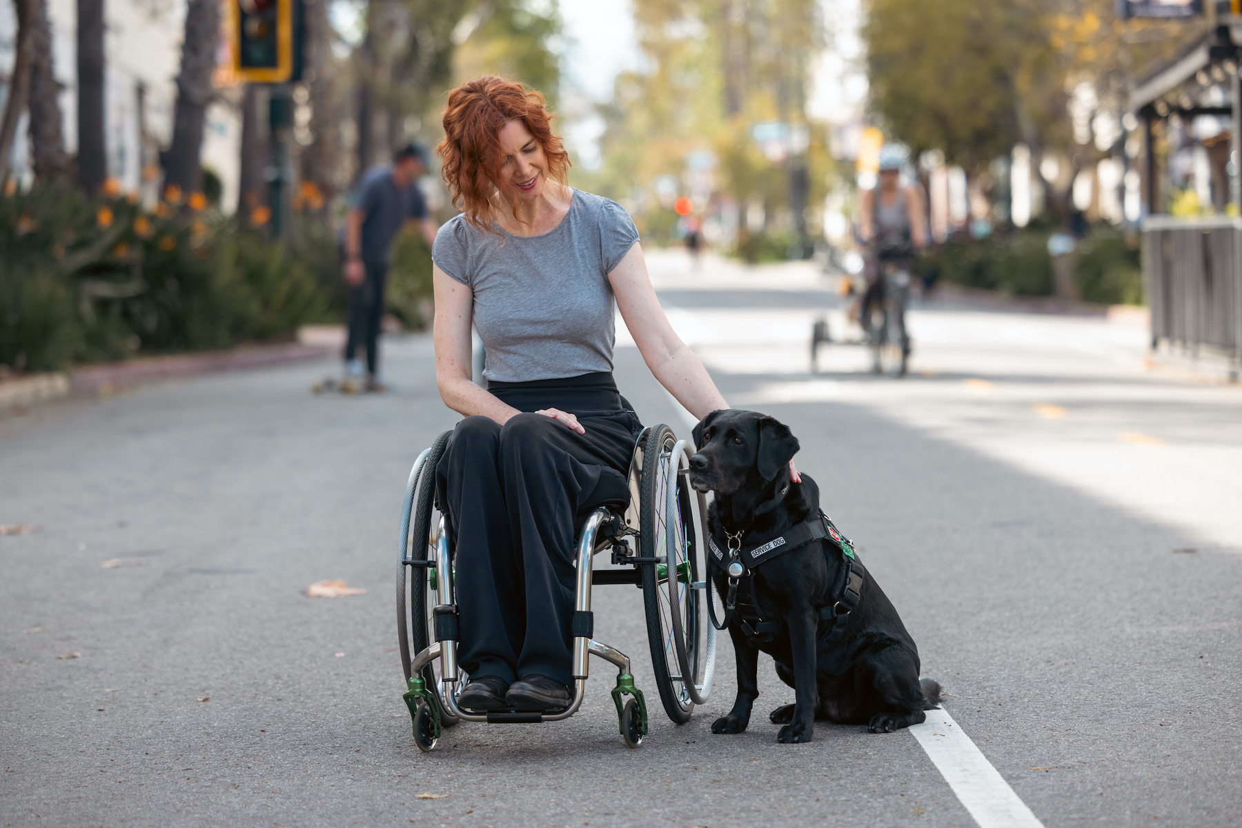 Woman on wheelchair strolling in the city with her service dog