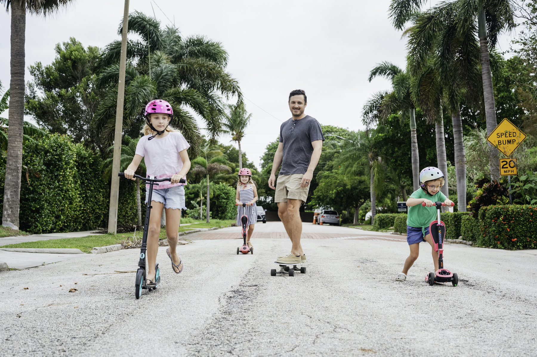 Kids with dad on scooters and skateboards