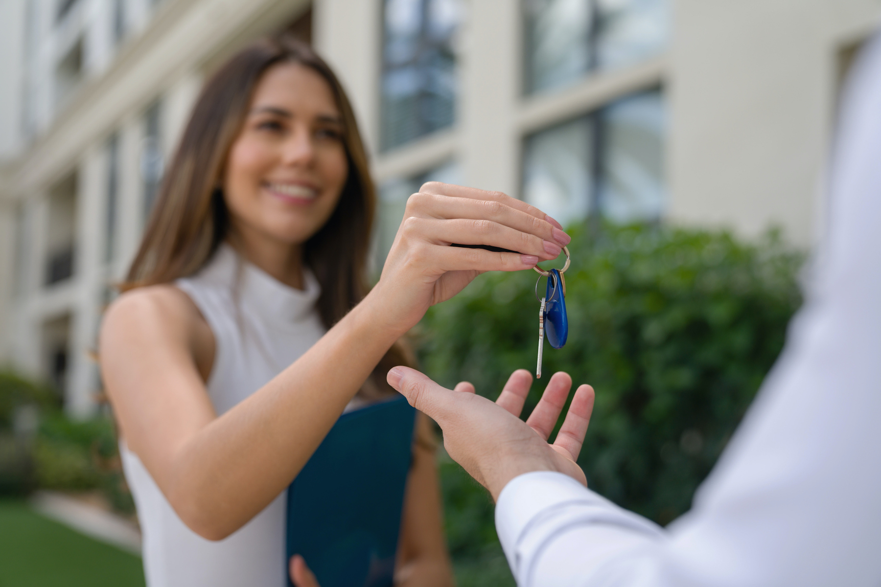 Real estate agent outdoors giving the keys of his new house to a client – home ownership concepts