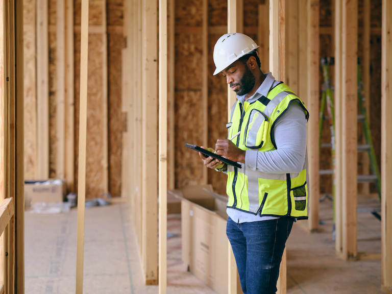 A construction worker inspecting a home under construction.